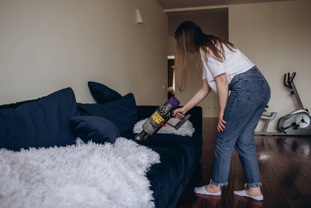 girl cleaning the sofa with a vacuum cleaner. - Fotoğraf, Görsel