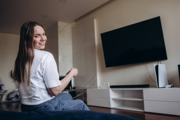 Young Woman Sitting On Couch Watching Movie On Television At Home. - Photo, Image