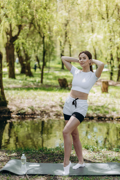 Young athletic woman doing longitudinal splits outdoors. Girl go in for sports, healthy lifestyle, athletic body. She is in sportswear, black top and shorts. Sport concept. - Photo, Image