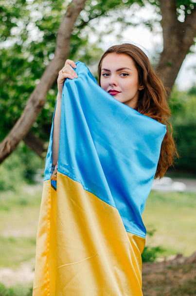 Meisje met de vlag van Oekraïne. Oekraïense vrouw met de vlag van Oekraïne. Vlag van Oekraïne. Patriottische foto van een Oekraïense vrouw met de vlag van Oekraïne - Foto, afbeelding