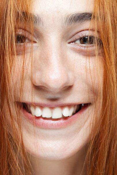 Beautiful dark burnt orange hair girl looking at camera. Studio portrait with happy smiling face expression on gray background. - Фото, изображение