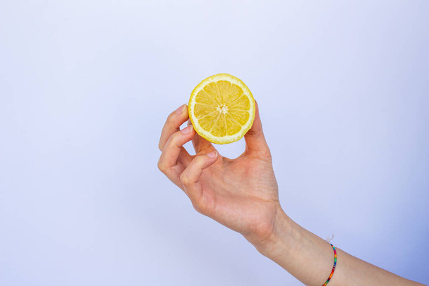 Крупним планом рука тримає половину лимона, ізольовані на білому тлі
. - Фото, зображення