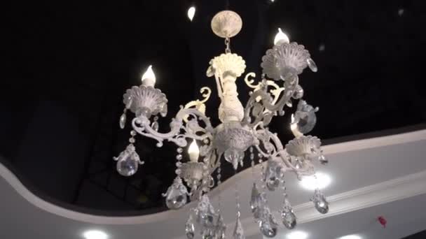 Close-up of beautiful crystal chandelier Beautiful chandelier. luxurious expensive chandelier suspended from ceiling. Old luxury on black glossy suspended ceiling. Camera flyby. - Séquence, vidéo
