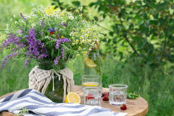 breakfast in the garden. on the table is a vase with daisies and glasses of lemonad - 写真・画像