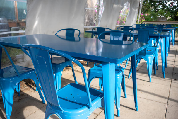 Vue colorée de chaises bleues lumineuses réunies autour d'une table bleue sur un patio extérieur dans un restaurant - Photo, image