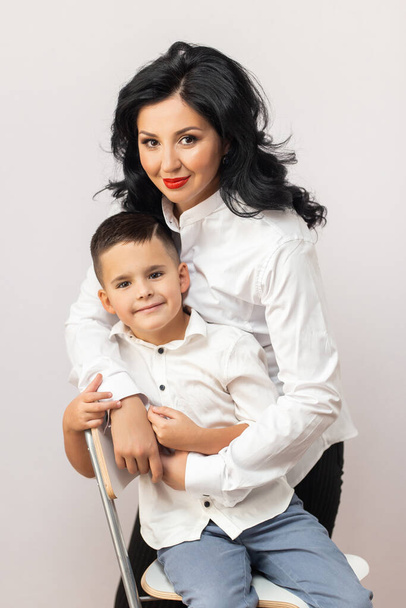 happy young mother with a child on light grey background - Фото, зображення