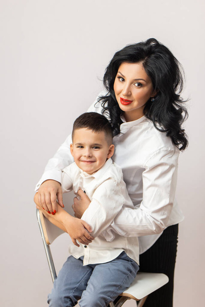 happy young mother with a child on light grey background - Фото, зображення