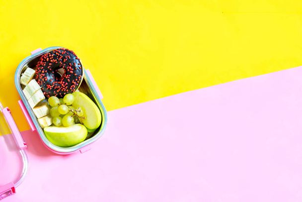 Catering food prepared in storage compartment container with doughnut,apple,banana on pink background mockup.meal with healthy balanced diet,lunch box boxed take away delivery packed ready.copy space. - Fotó, kép