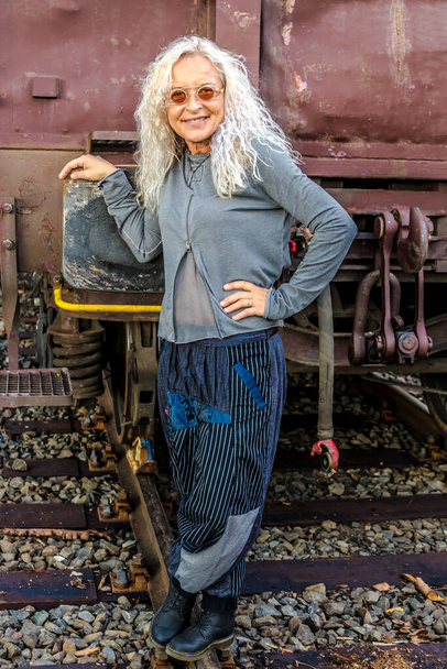 Hermosa dama en los años 50 de pie frente al tren de carga de la industria en el fondo - Foto, Imagen
