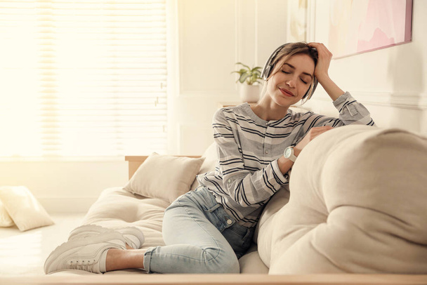 Молода жінка слухає музику на дивані вдома
 - Фото, зображення
