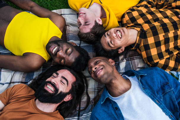 Група молодих людей різних національностей лежить на підлозі
 - Фото, зображення