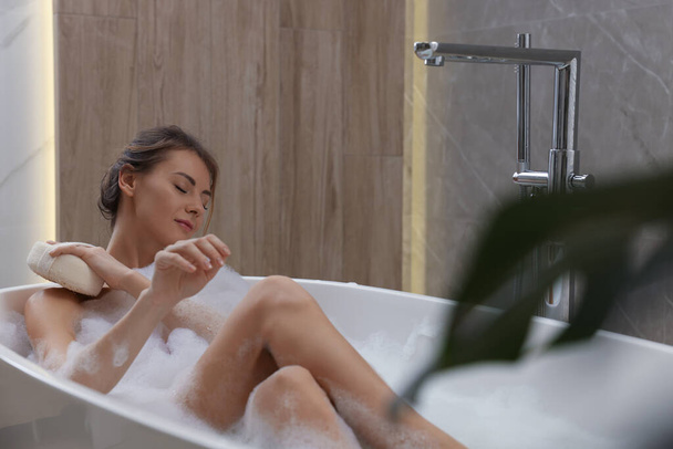 Beautiful woman with sponge taking bath indoors, space for text - Φωτογραφία, εικόνα