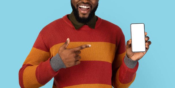 Usmívající se černoch ukazuje na prázdný mobil s bílou obrazovkou v jeho ruce, Happy Excited Young African American Male doporučuje nové mobilní aplikace nebo webové stránky, oříznutý výstřel, Panorama, Mockup - Fotografie, Obrázek