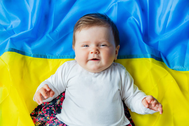 ウクライナの旗の上に少女が横たわっていた。トップ表示 - 写真・画像