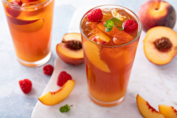 Peach and raspberry iced tea or cocktail, cold and refreshing summer drink - Фото, зображення