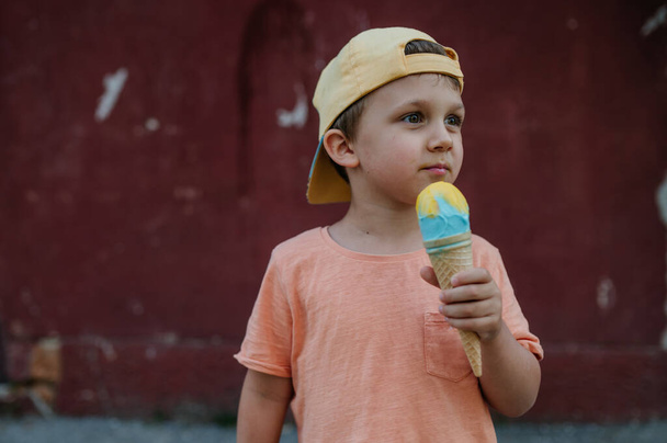 A little cute boy with ice cream outdoors in summer - Fotoğraf, Görsel