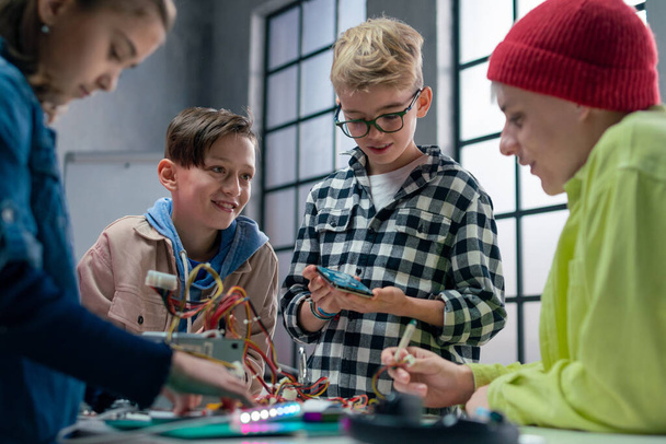 A group of happy kids with their science teacher with electric toys and robots at robotics classroom - Foto, afbeelding