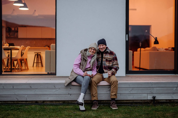 A happy senior couple sitting on terrace and drinking coffee together. - Foto, afbeelding
