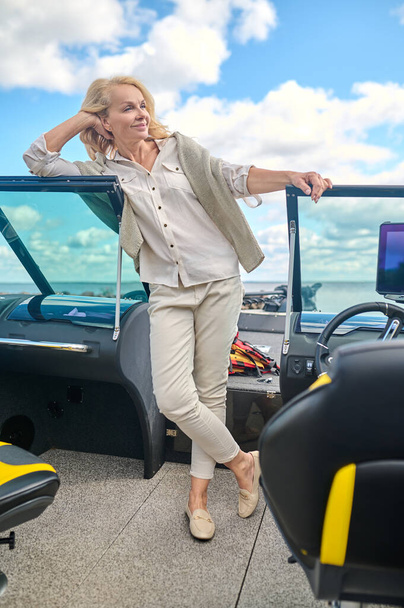 A boat trip. A blonde pretty woman standing on a boat deck and smiling - Fotoğraf, Görsel