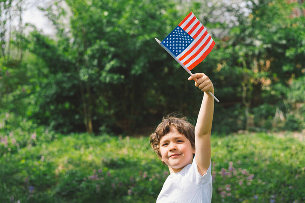 Happy little patriotic boy holding American flag. USA celebrate 4th of July. Happy independence day - Photo, Image