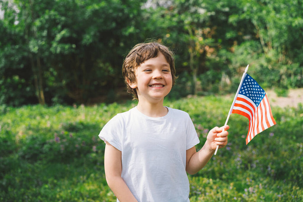Glücklicher kleiner patriotischer Junge mit amerikanischer Flagge. USA feiern den 4. Juli. Glücklicher Unabhängigkeitstag - Foto, Bild