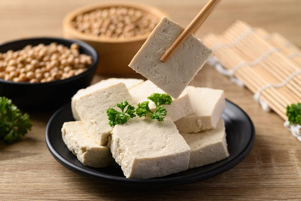 Tofu casero con palillos, ingredientes veganos en la cocina asiática, a base de plantas - Foto, Imagen