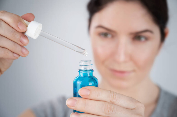 Caucasian woman uses blue anti-wrinkle face serum - Foto, afbeelding