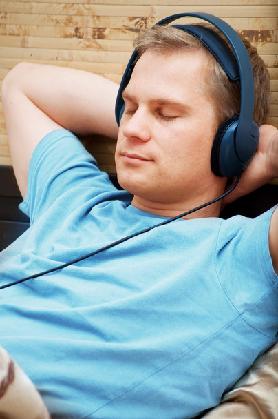 Laying young man listening music - Фото, зображення