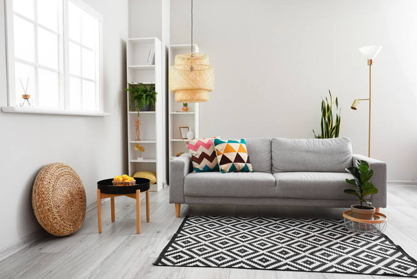 Интерьер современной гостиной с удобным диваном, лампой и комодом - Фото, изображение