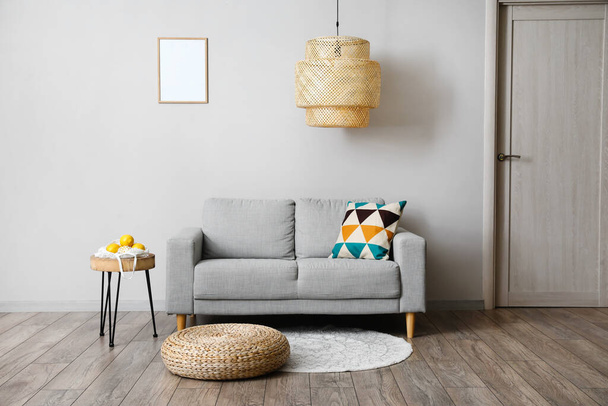 Canapé confortable, table et lampe moderne près du mur gris - Photo, image