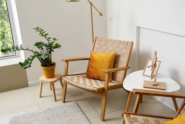 Kényelmes fotelek, asztal és szobanövény a fényfal közelében - Fotó, kép
