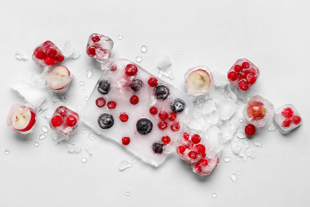 軽い背景で氷の中で凍結した新鮮な果実 - 写真・画像