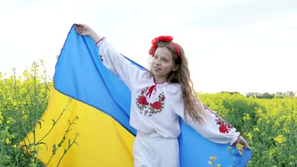Bid voor Oekraïne. Kind met Oekraïense vlag in koolzaadveld. Meisje met nationale vlag biddend voor vrede. - Video