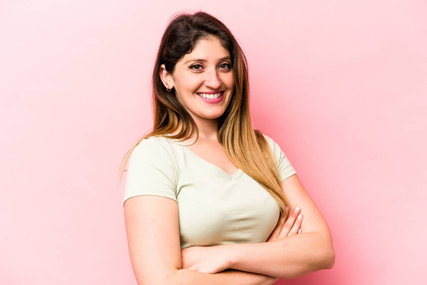 Young caucasian woman isolated on pink background who feels confident, crossing arms with determination. - Photo, Image