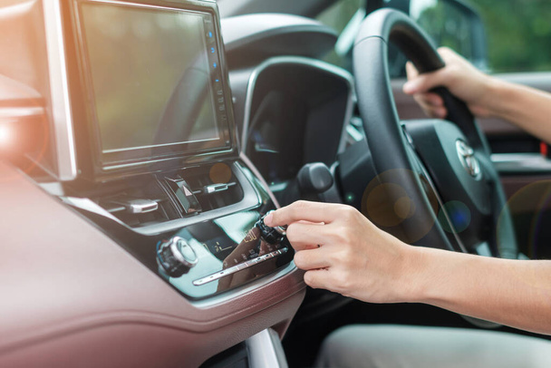 Woman hand adjusting temperature the air flowing during driving car on the road, air conditioner cooling system inside the car. Adjust, temperature and transport concept - Foto, Imagem