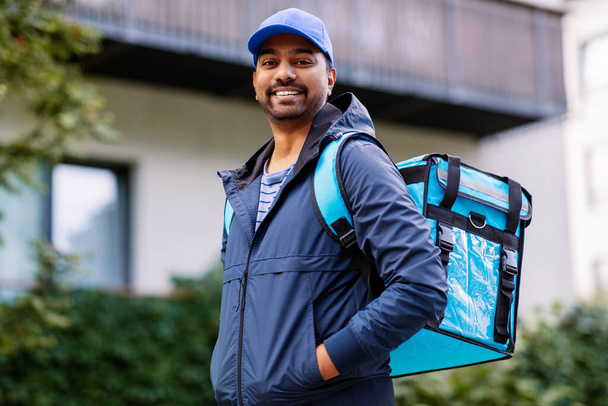 food shipping, profession and people concept - happy smiling indian delivery man with thermal insulated bag on city street - Fotoğraf, Görsel