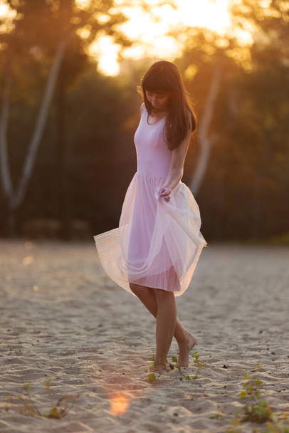szép fiatal divatos nő elegáns ruhában séta a tengerparton naplementekor - Fotó, kép