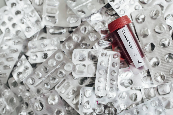 Transparante glazen injectieflacons met etiketten en een test COVID-19 vaccin, spuit op een bureau - Foto, afbeelding