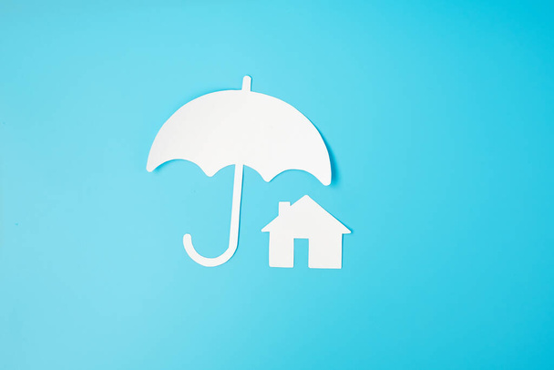 傘カバー青の背景にホームペーパー。保証、メンテナンス、不動産および保険の概念 - 写真・画像
