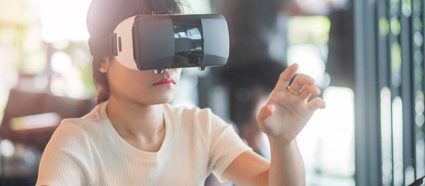 Young woman using virtual reality headset. VR, Future digital technology, game, entertainment, metaverse, NFT and 3D cyberspace concept - Photo, Image