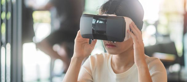Sanal gerçeklik kulaklığı kullanan genç bir kadın. VR, gelecekteki dijital teknoloji, oyun, eğlence, metaevren, NFT ve 3D siber uzay kavramı - Fotoğraf, Görsel
