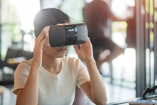 Jeune femme utilisant un casque de réalité virtuelle. VR, Future digital technology, game, entertainment, metaverse, NFT et 3D cyberspace concept - Photo, image