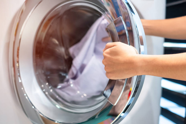 Housewife Woman hand holding clothes inside Washing Machine in laundry room - Foto, imagen
