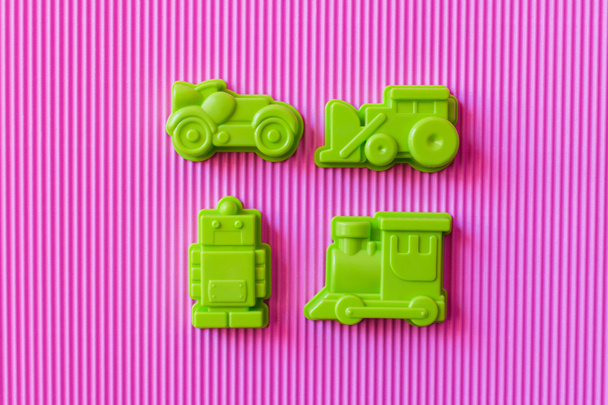 vista dall'alto del robot giocattolo verde vicino a veicoli di plastica su sfondo con texture viola - Foto, immagini