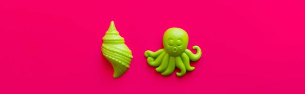 top view of bright green shellfish and octopus toys on pink background, banner - Photo, Image