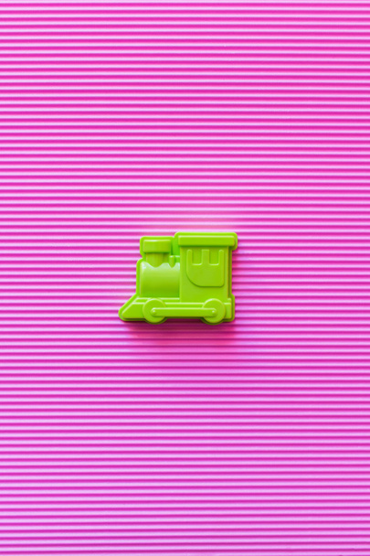 vista superior de locomotora de juguete verde brillante sobre fondo texturizado violeta - Foto, Imagen