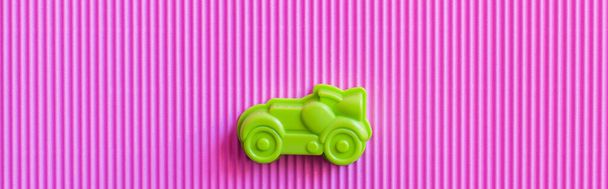 bovenaanzicht van groene vintage speelgoedauto op violette golfachtergrond, banner - Foto, afbeelding