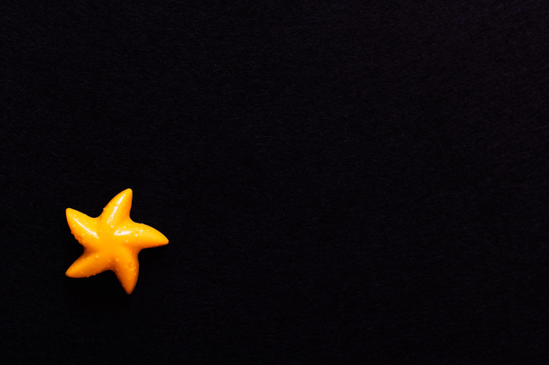 vista dall'alto dello stampo giallo brillante a forma di stella marina isolata sul nero - Foto, immagini