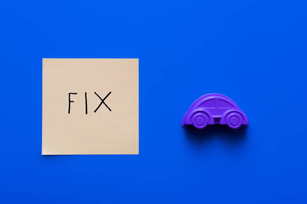 top view of purple plastic car near card with fix lettering on blue background - Photo, Image