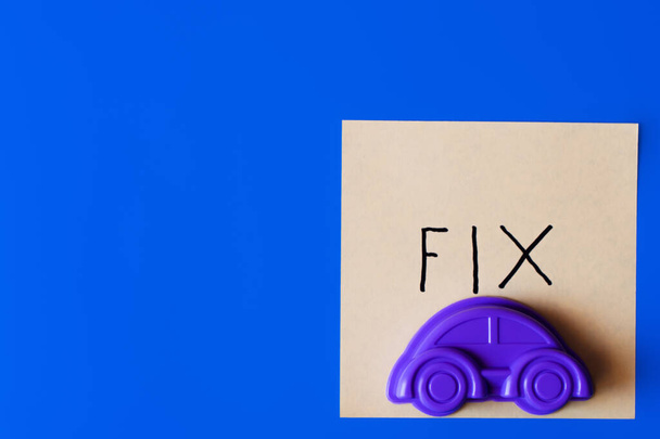 Draufsicht auf violettes Spielzeugauto und Papier mit festem Schriftzug auf blauem Hintergrund - Foto, Bild